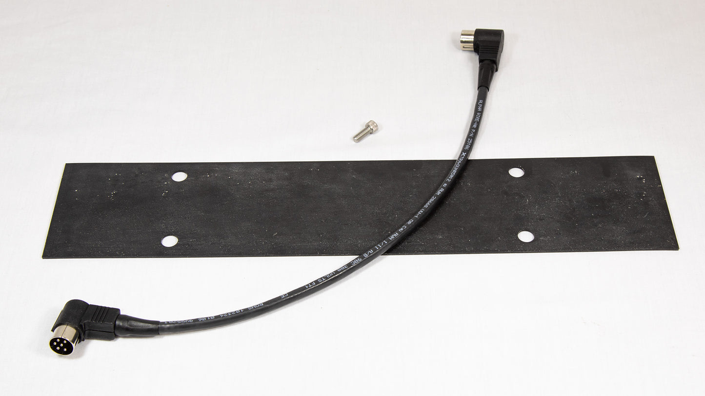 A black plastic plate accompanied by one screw and a cord, positioned on a simple surface.