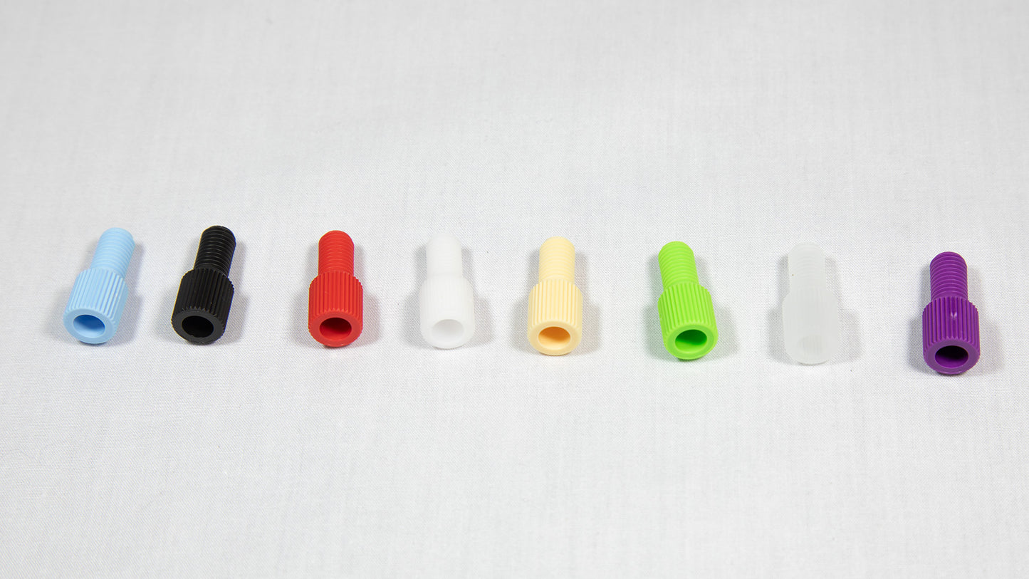 A variety of plastic plugs in multiple colors displayed on a white surface, emphasizing their unique forms and shades.