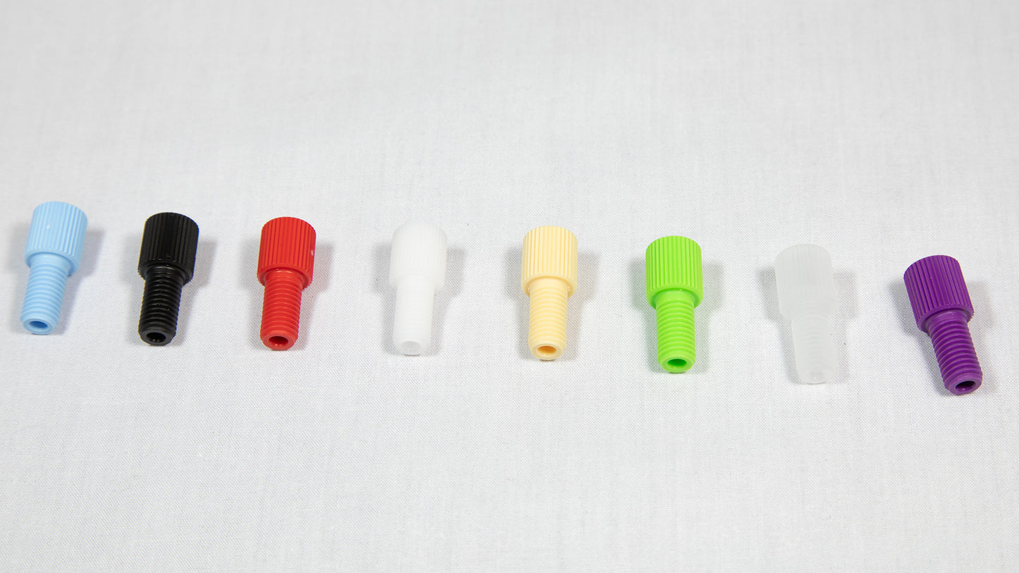 A variety of plastic plugs in multiple colors displayed on a white surface, emphasizing their unique forms and shades.