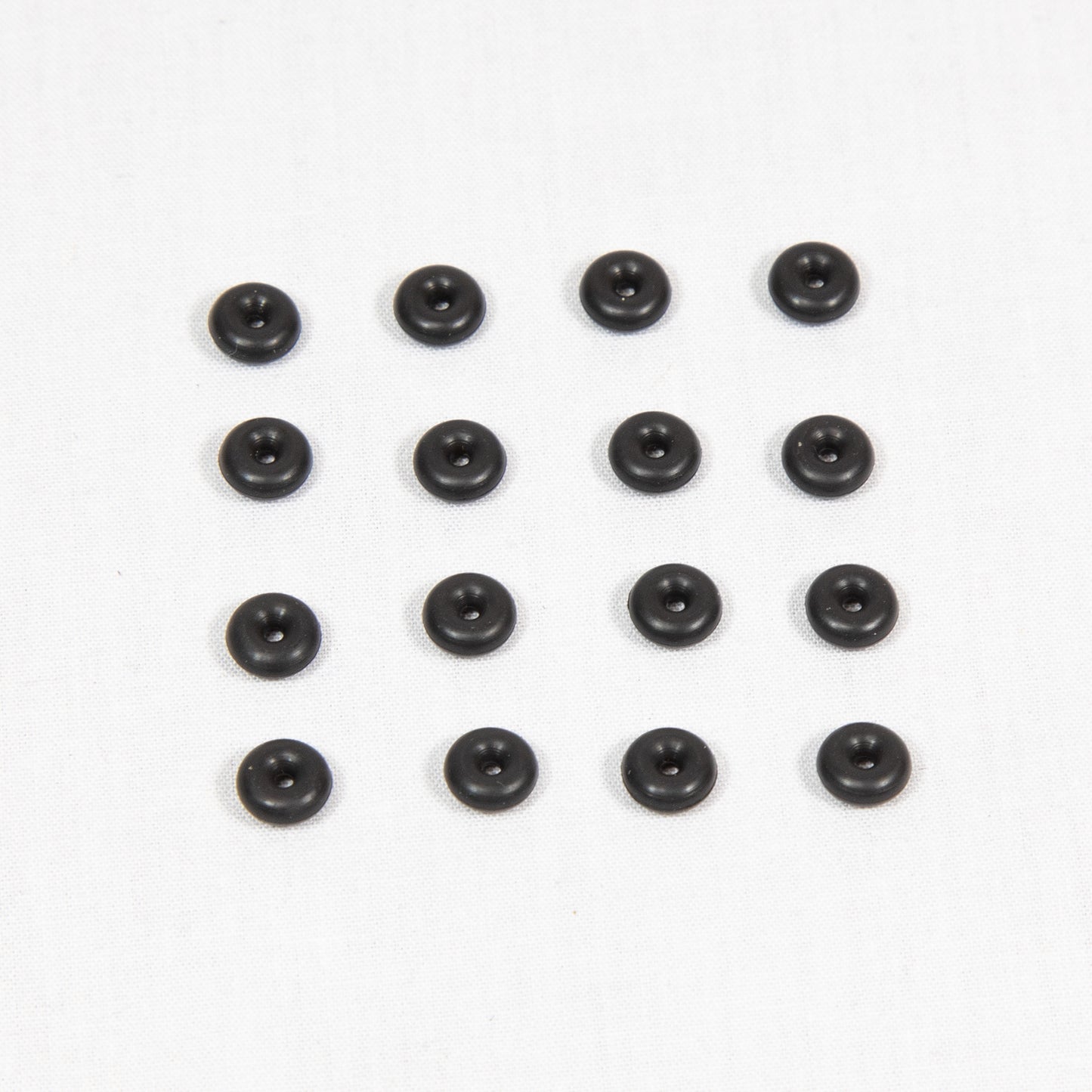 A collection of round black plastic objects arranged on a clean white surface.