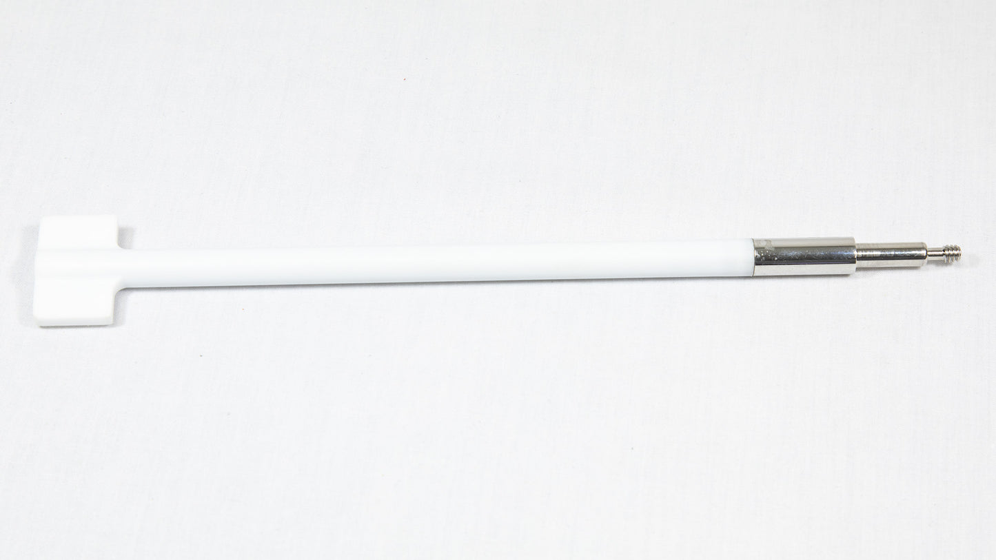 A white rod with a metal tip rests on a smooth white surface, highlighting its sleek design and minimalistic style.