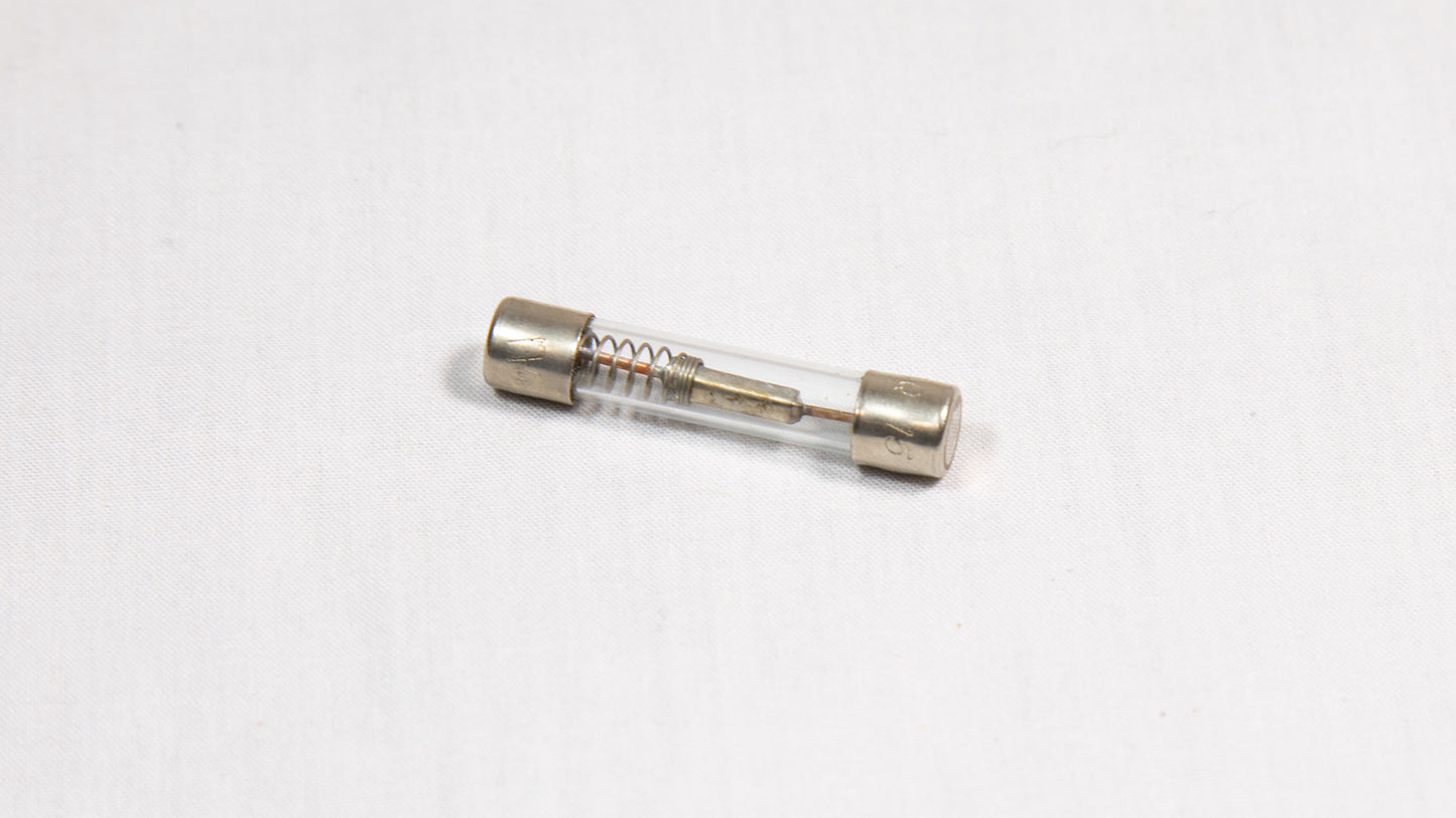 A slender electronic fuse with tiny metal tips, highlighting its functional and straightforward appearance.