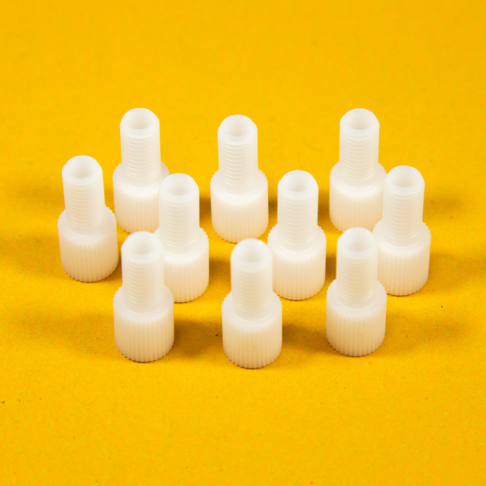 A collection of white plastic threaded fittings arranged on a bright yellow background.