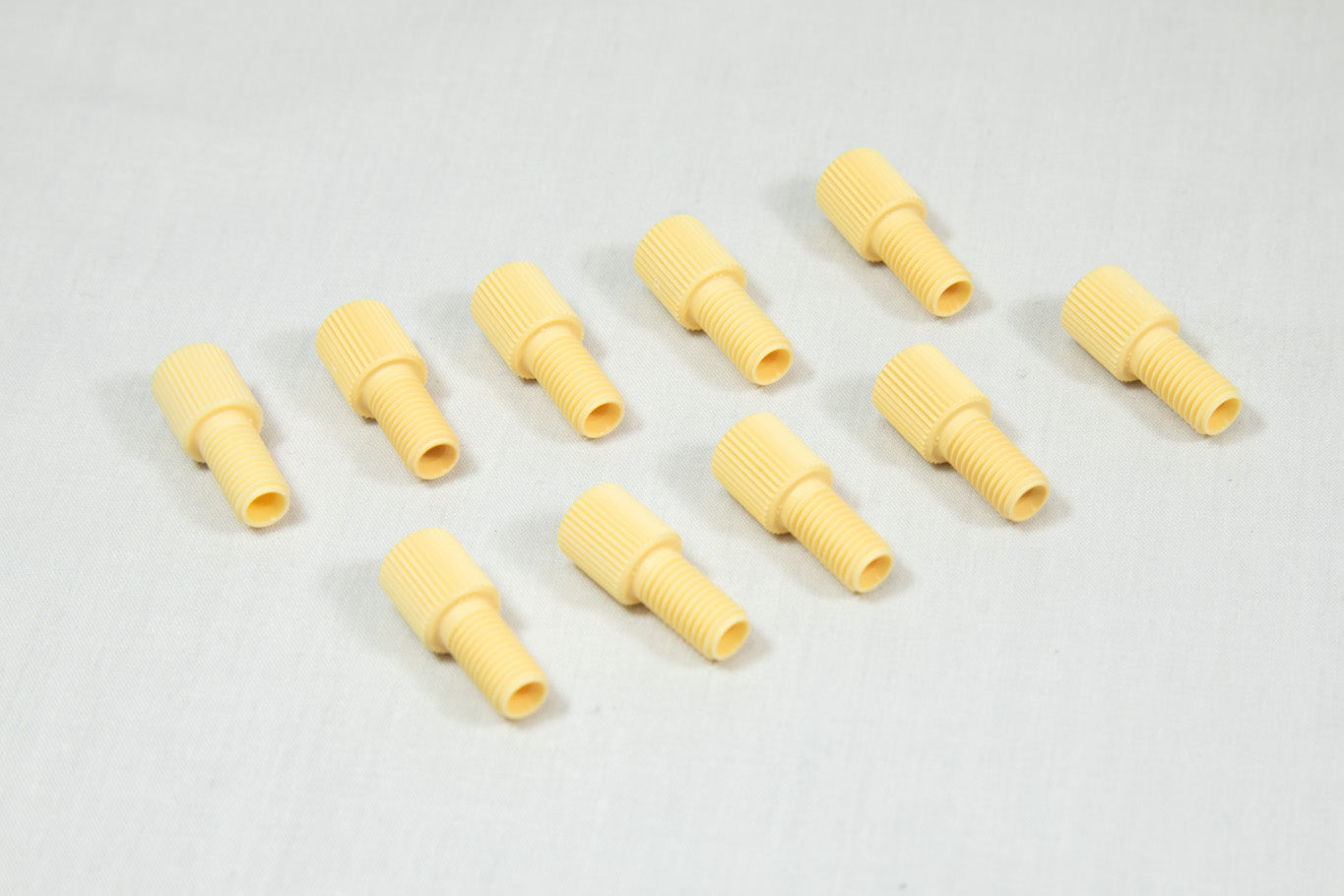 A collection of yellow plastic threaded fittings arranged on a clean white surface.