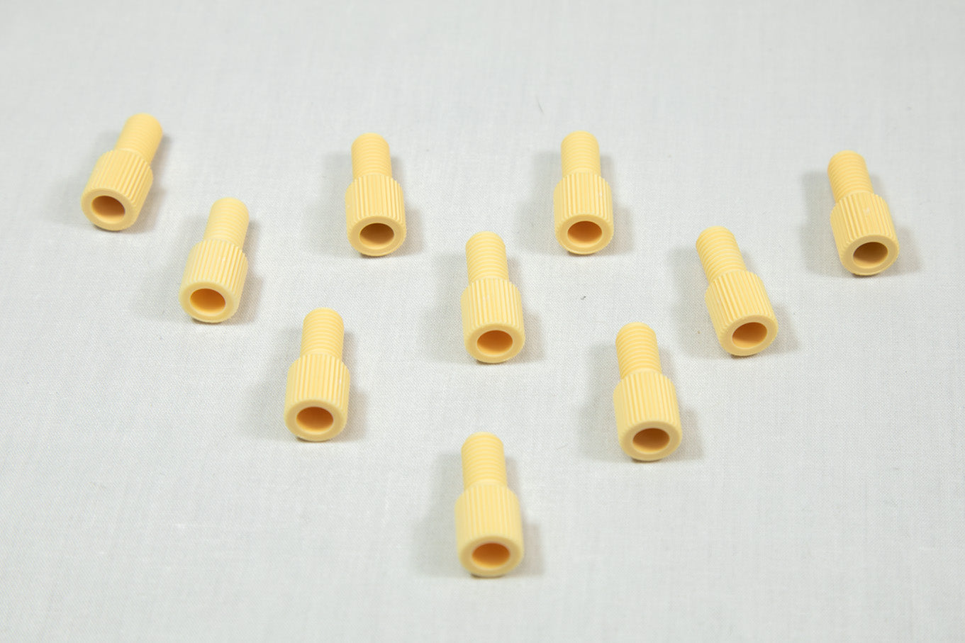 A collection of yellow plastic threaded fittings arranged on a clean white surface.
