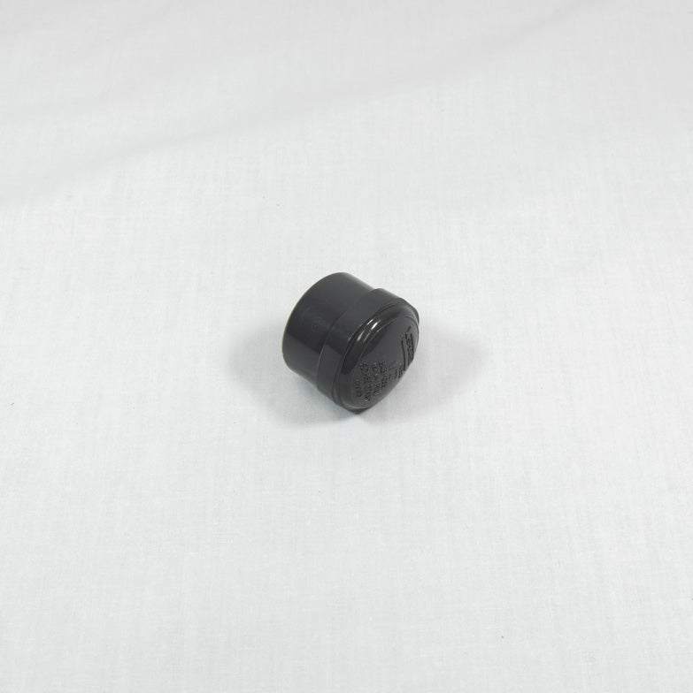 A solitary black plastic nut displayed on a white background.