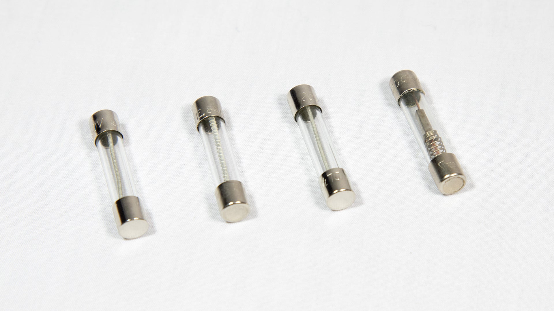 Four distinct electronic fuses arranged on a white surface.