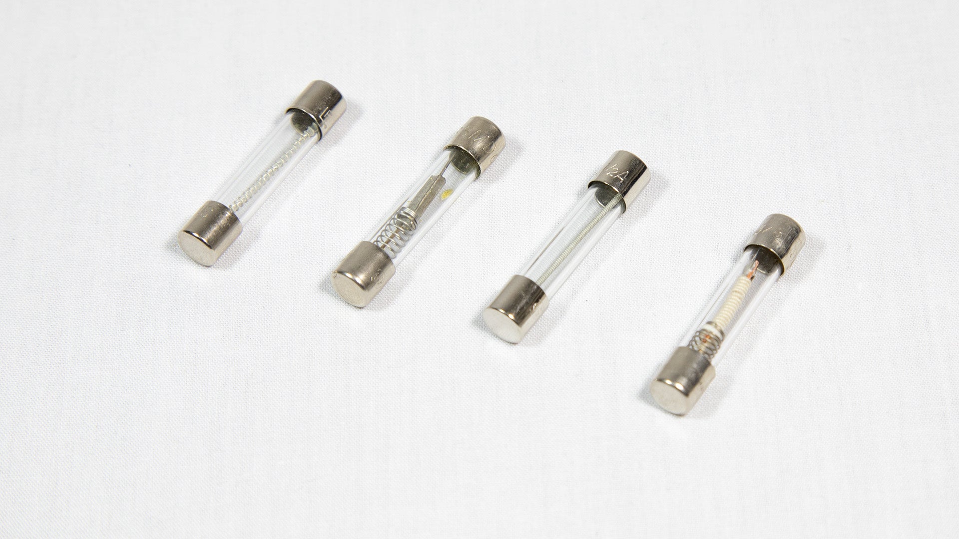 Four distinct electronic fuses arranged on a white surface.