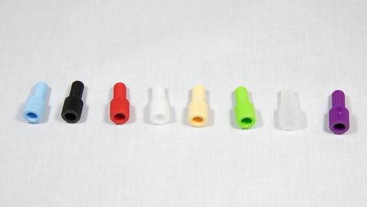A variety of plastic plugs in multiple colors displayed on a white surface, emphasizing their unique forms and shades.
