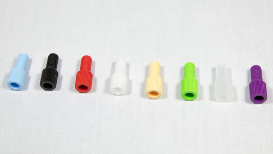 A variety of plastic plugs in multiple colors displayed on a white surface, emphasizing their unique forms and shades.