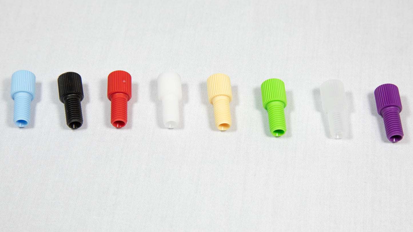 A variety of plastic plugs in multiple colors displayed on a white surface, emphasizing their unique forms and shades.