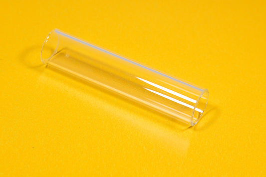 A clear tube resting on a bright yellow surface, showcasing its transparency and smooth texture.