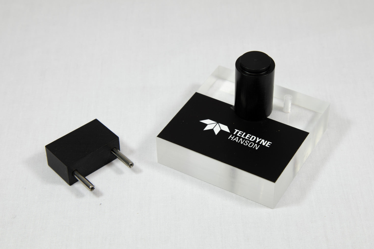 A black and white object positioned beside a small black object, emphasizing the difference in color and scale.