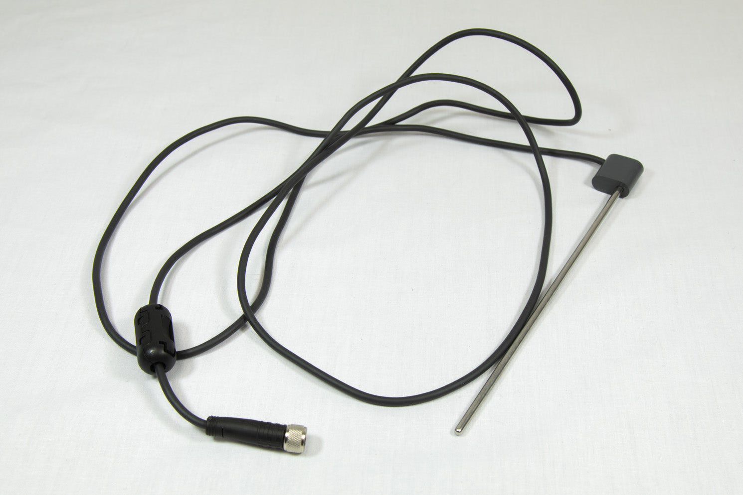 A black cord with a steel rod and connector, coiled and resting on a white surface.