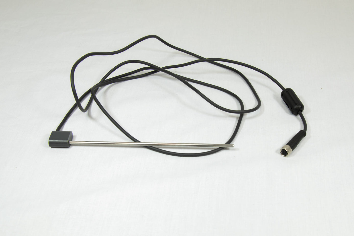 A black cord with a steel rod and connector, coiled and resting on a white surface.