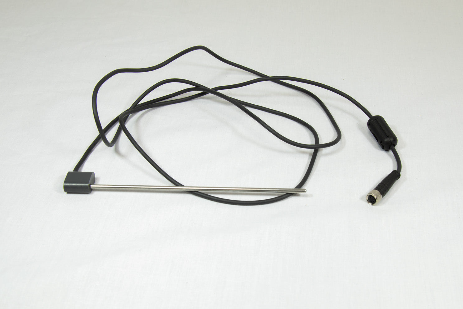 A black cord with a steel rod and connector, coiled and resting on a white surface.
