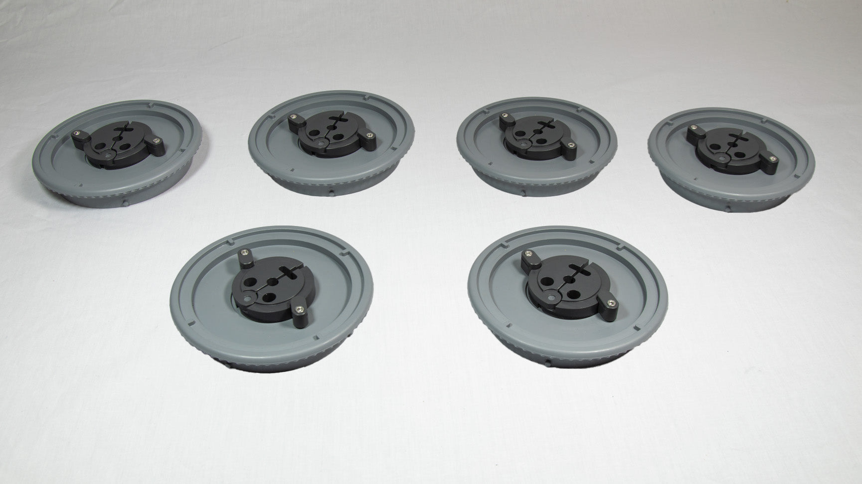 A collection of six gray plastic plates, each with holes and screws, displayed together on a plain background.