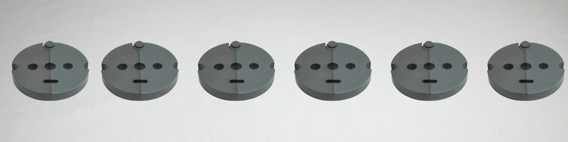 A collection of six gray plastic plates, each with holes and screws, displayed together on a plain background.