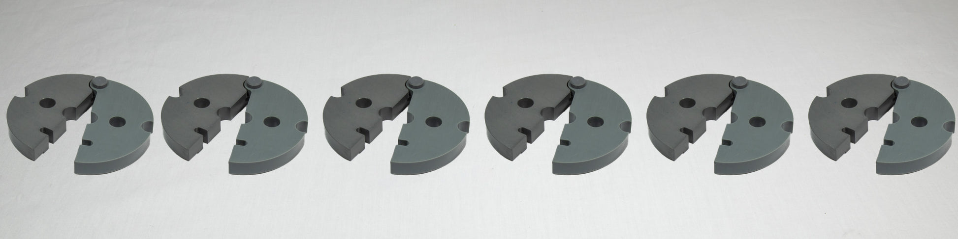 A collection of six gray plastic plates, each with holes and screws, displayed together on a plain background.