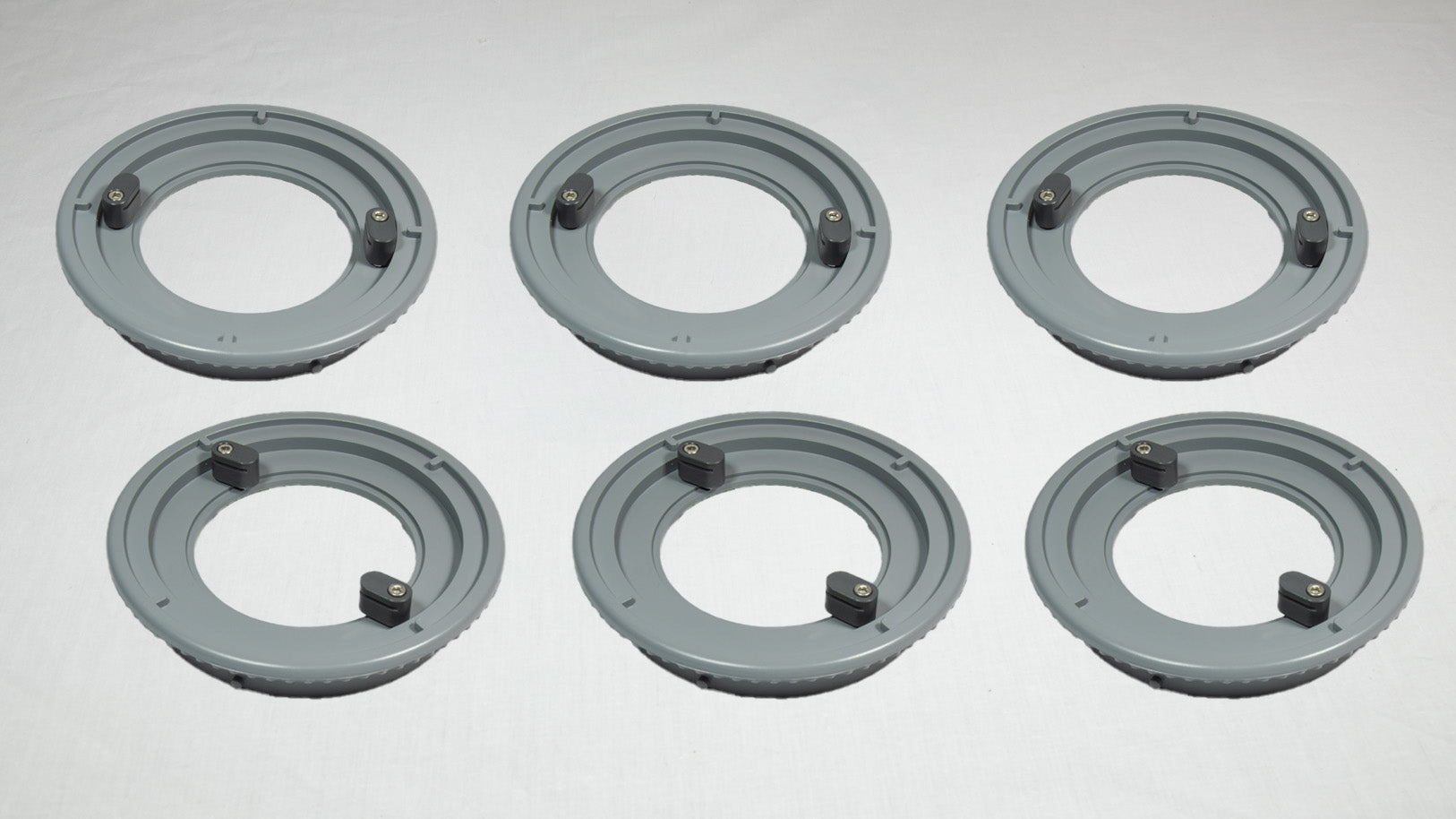 Six gray plastic rings arranged on a white surface, showcasing their circular shape and smooth texture.