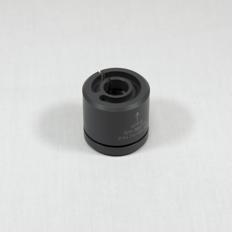 A black plastic cylinder with a prominent arrow indicating direction that includes a small hole.