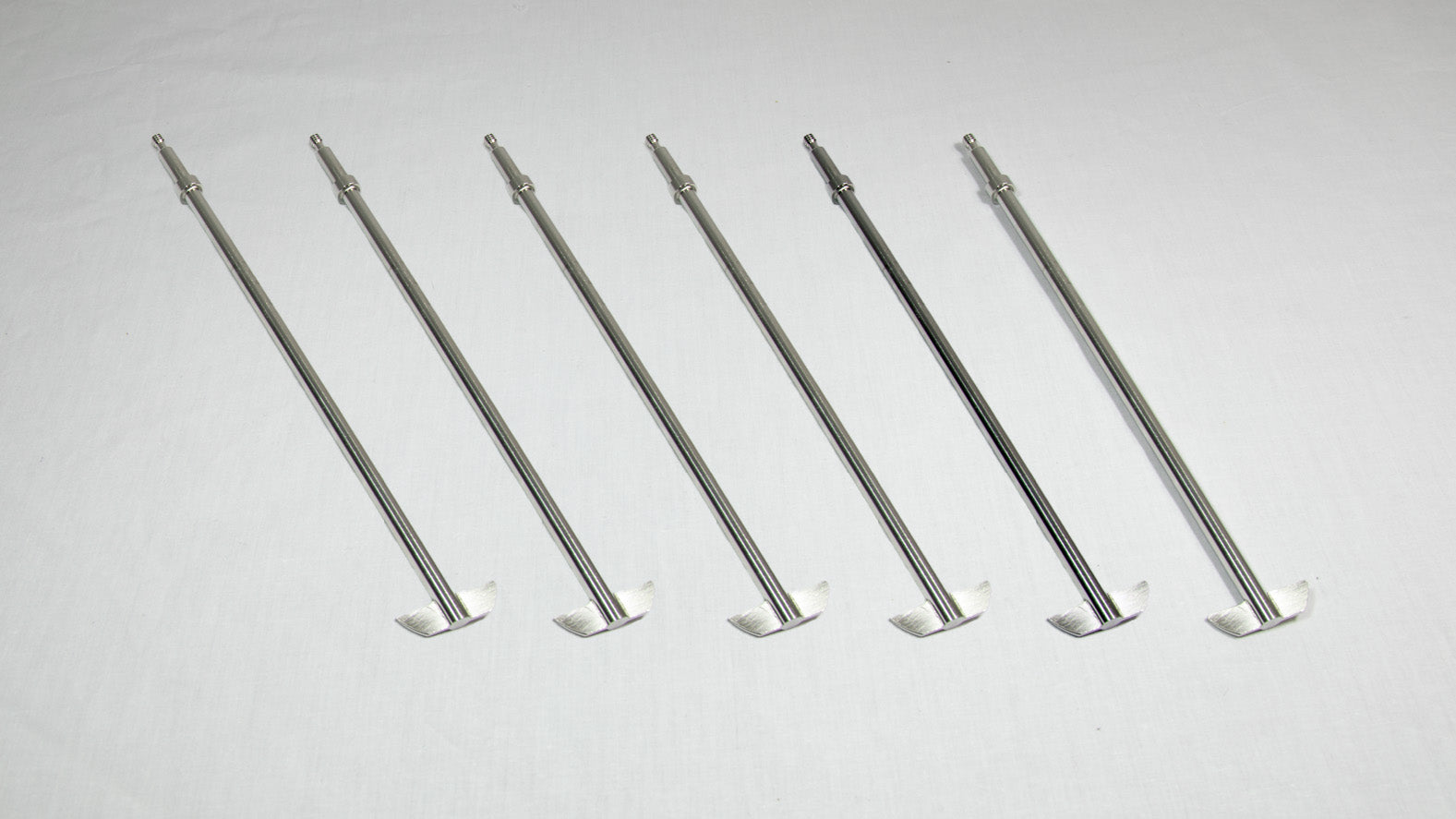Six stainless steel rods arranged neatly on a white surface, showcasing their sleek and shiny appearance.