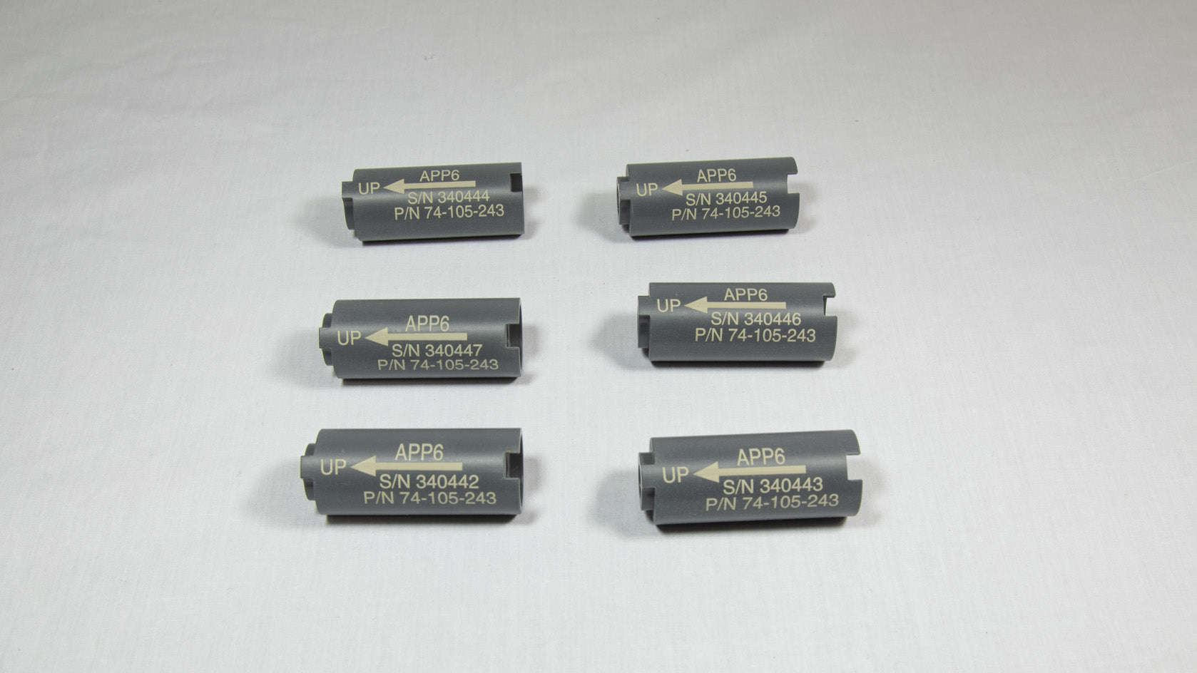 Six cylindrical black plastic objects, each with a perforation in the middle.