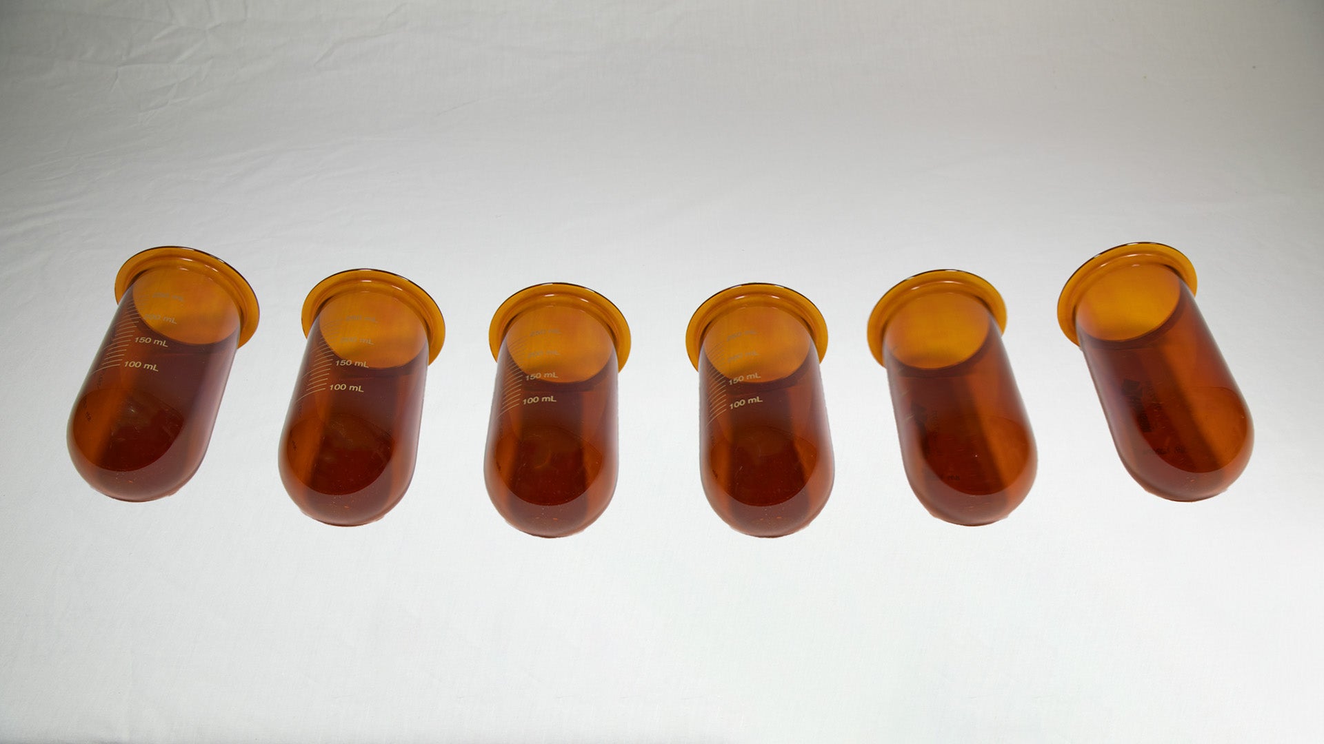 Several amber colored vessels lined up side by side.