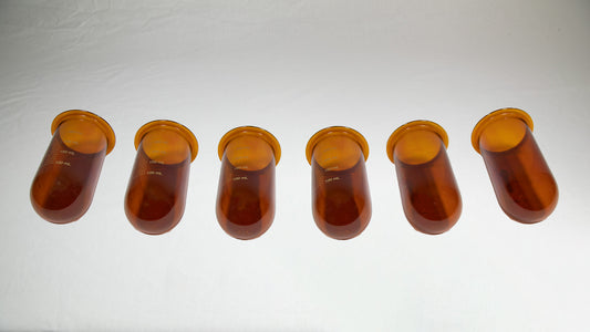 Several amber colored vessels lined up side by side.