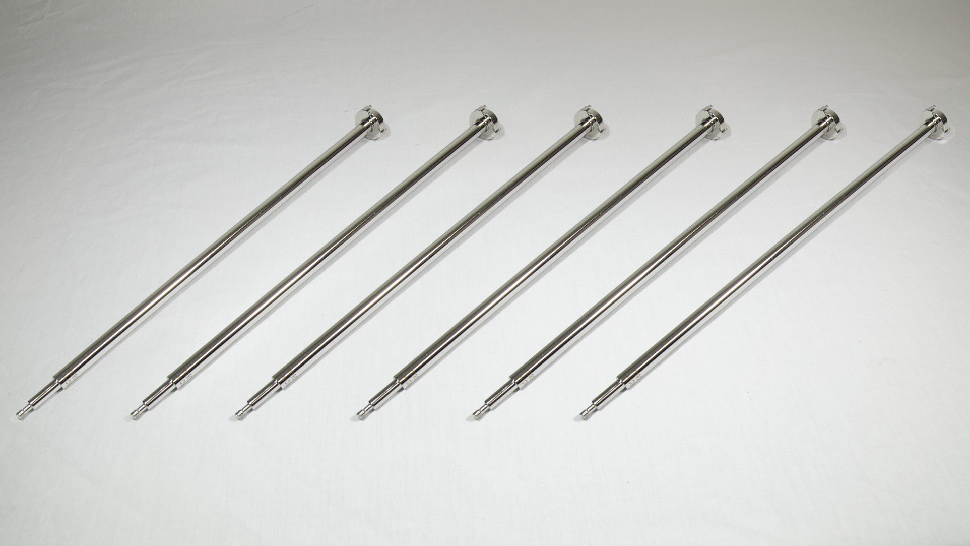 Six uniquely shaped metal rods positioned together for comparison.
