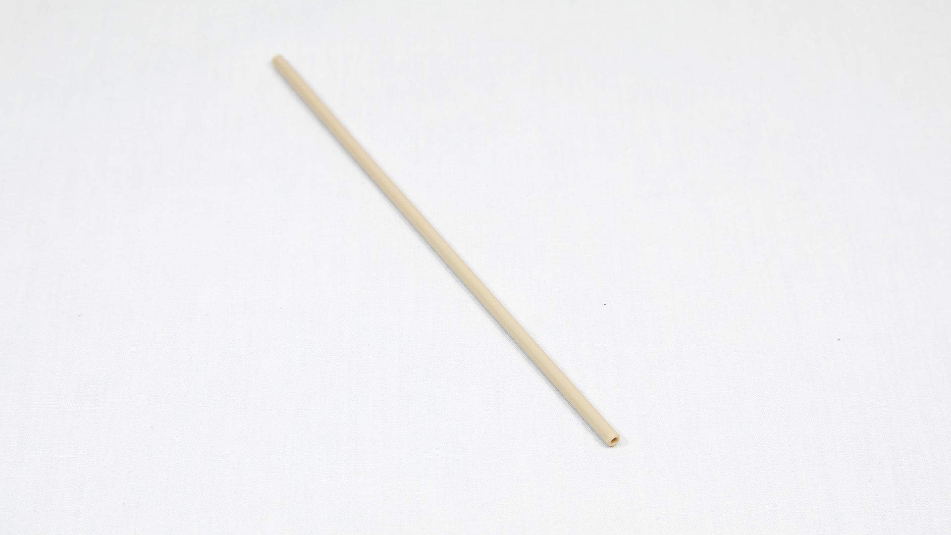 A long cylindrical shaped object pictured on a white background, creating a minimalist composition of everyday items.