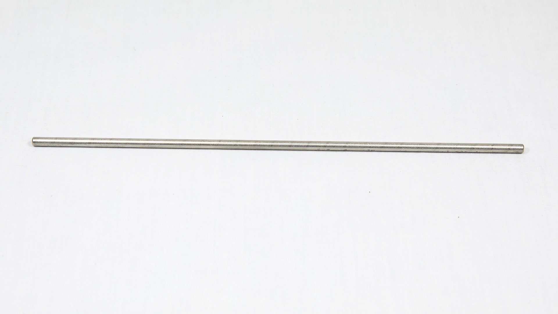A long cylindrical shaped object pictured on a white background, creating a minimalist composition of everyday items.