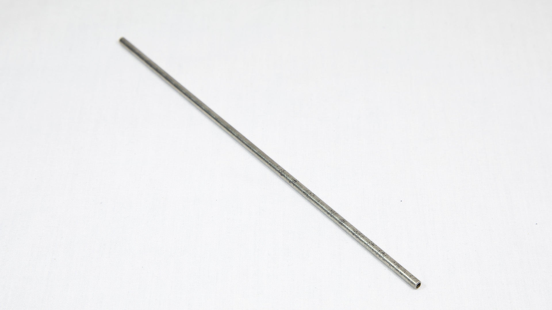 A long cylindrical shaped object pictured on a white background, creating a minimalist composition of everyday items.