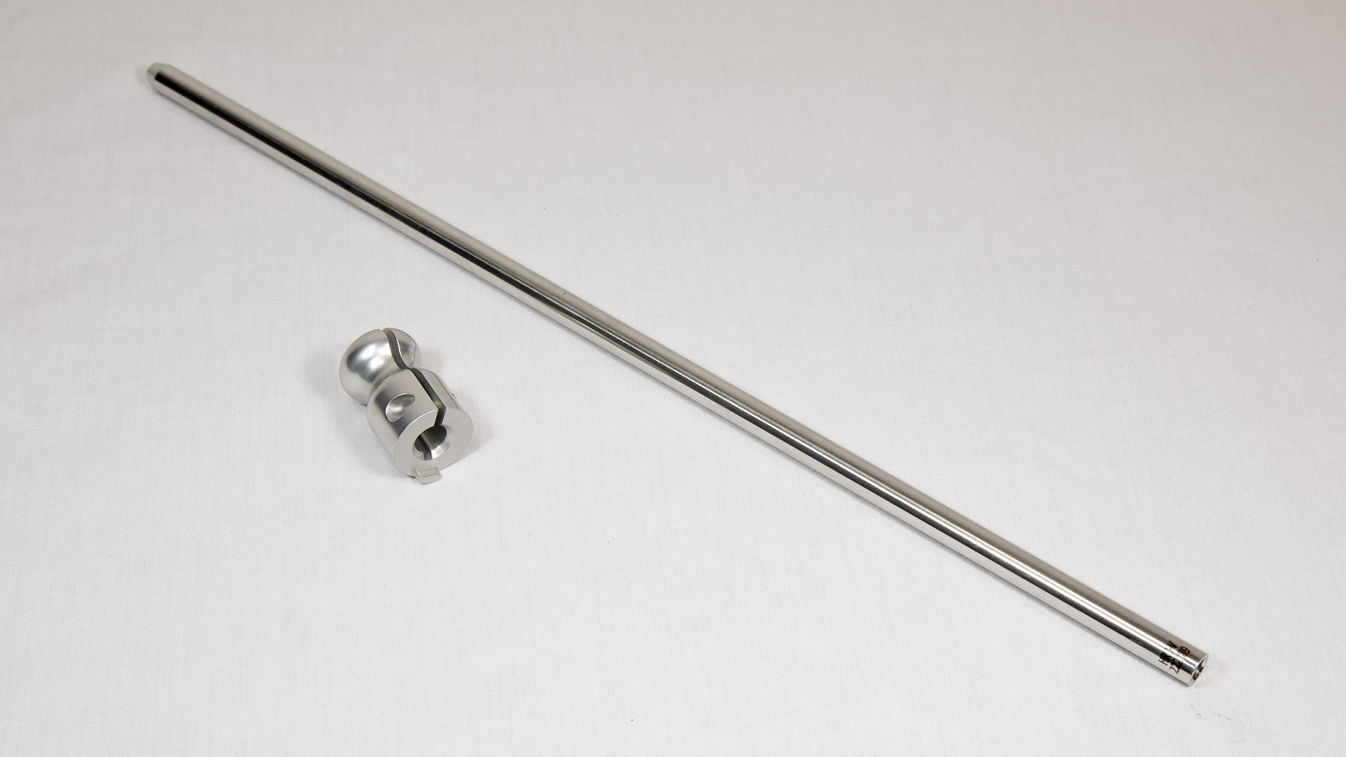 A stainless steel rod with a clamp resting on a white surface, showcasing its sleek design and functionality.