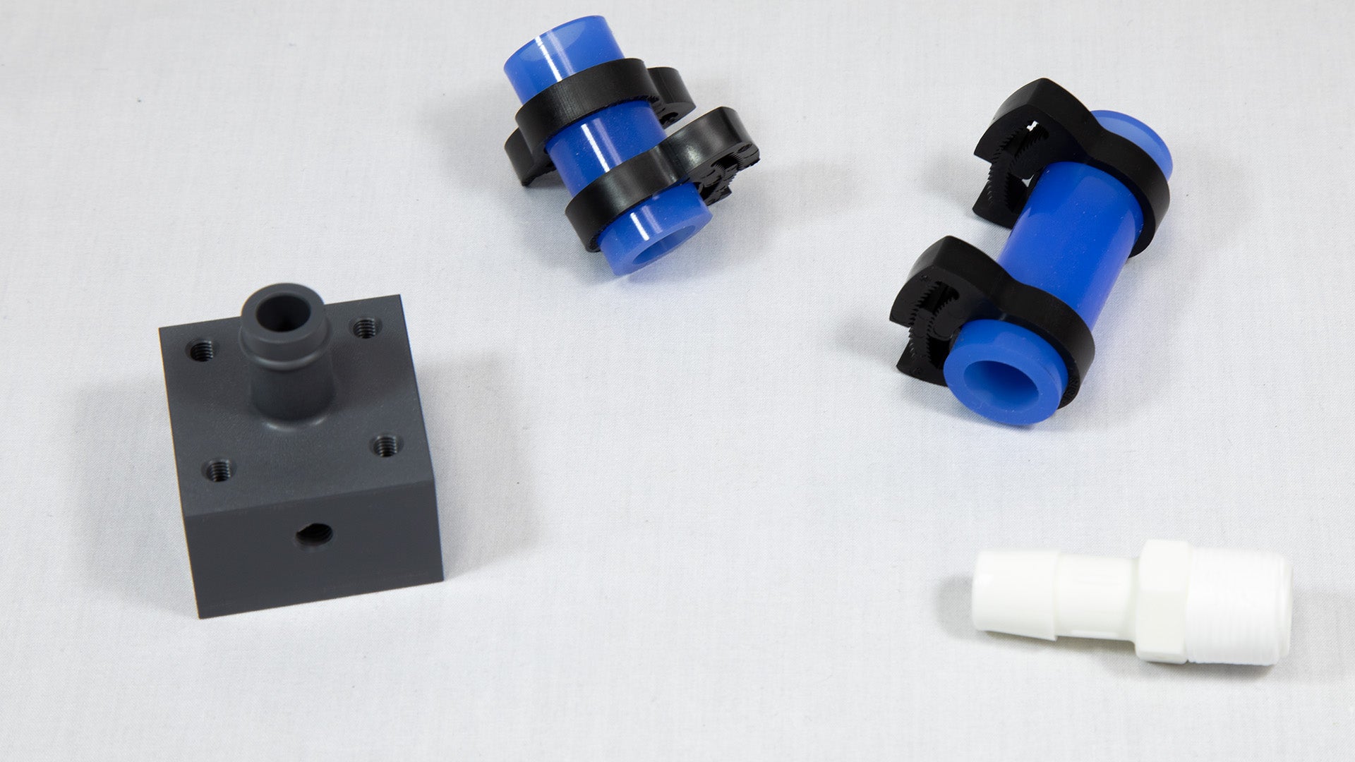 Sections of blue plastic tubing next to white and black connector components, showcasing their contrasting colors and materials.