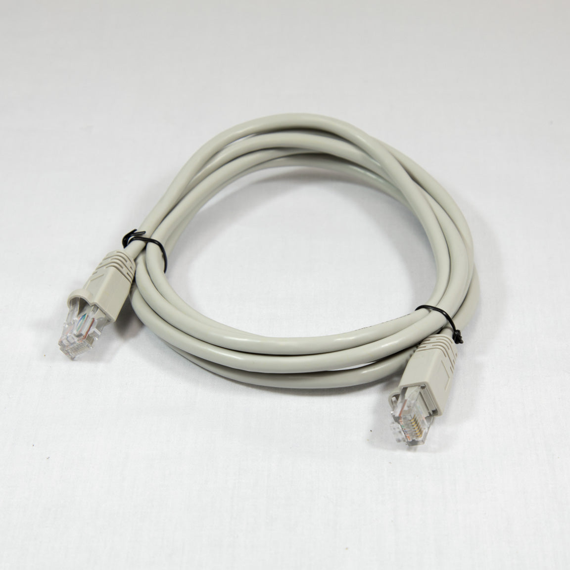 A tan Ethernet cable with connectors on both ends, coiled neatly on a surface.